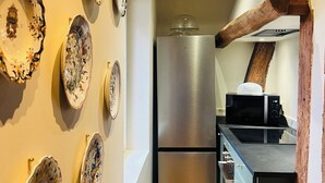 A kitchen with a stainless steel refrigerator, wooden beams on the ceiling, and a microwave on the counter. - Le Cotin Bleu. Duplex. Old Market. Sleeps 4/6 (Rouen)