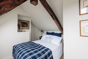 Un dormitorio con cama, mesita de noche, lámpara y un cuadro en la pared.