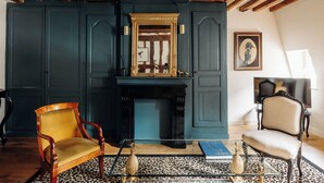 A room with a fireplace, two chairs, a mirror, and a television. - Le Cotin Bleu. Duplex. Old Market. Sleeps 4/6 (Rouen)
