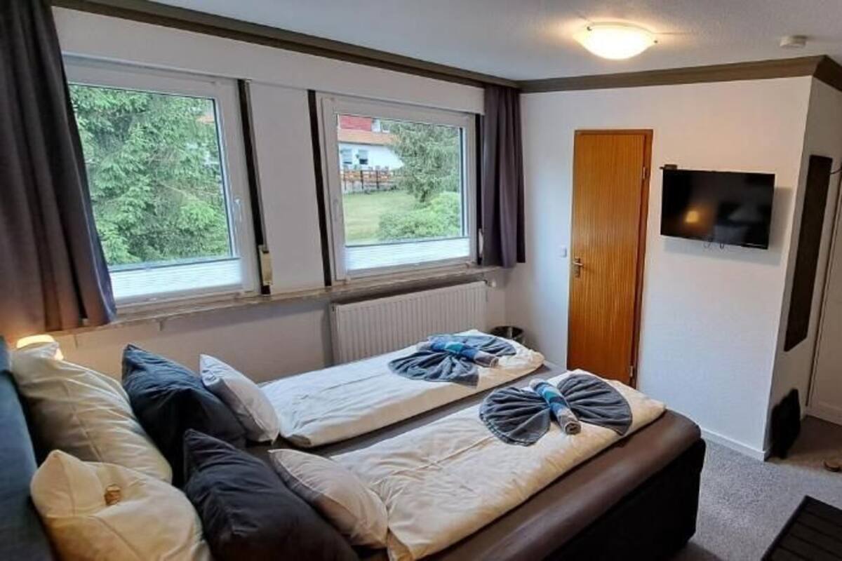 Une chambre avec deux lits, une télévision et une porte donnant sur une autre pièce.