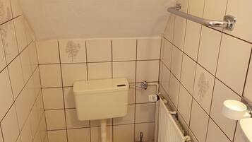 Un baño pequeño con azulejos, un inodoro, un bidé y un radiador.
