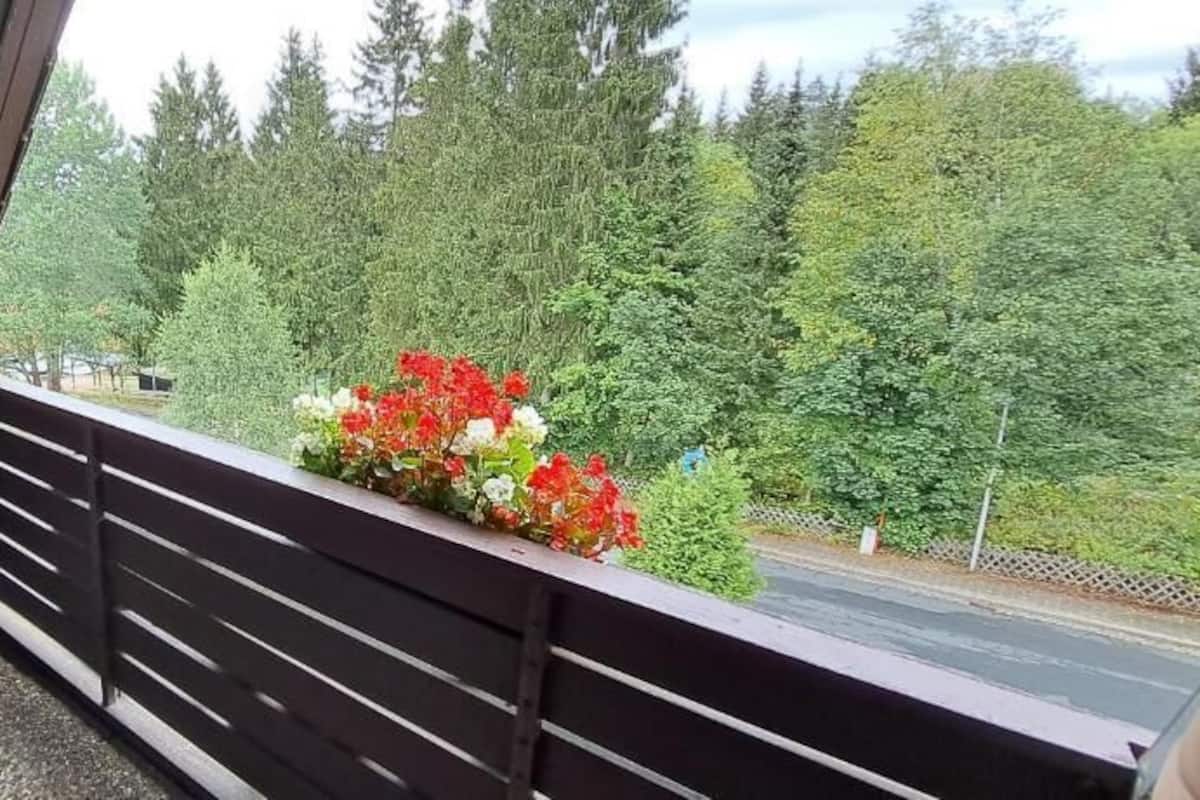 Un balcon agrémenté de meubles en osier et d’une composition florale.