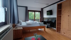 Een slaapkamer met een bed, bureau, televisie en garderobekast.
