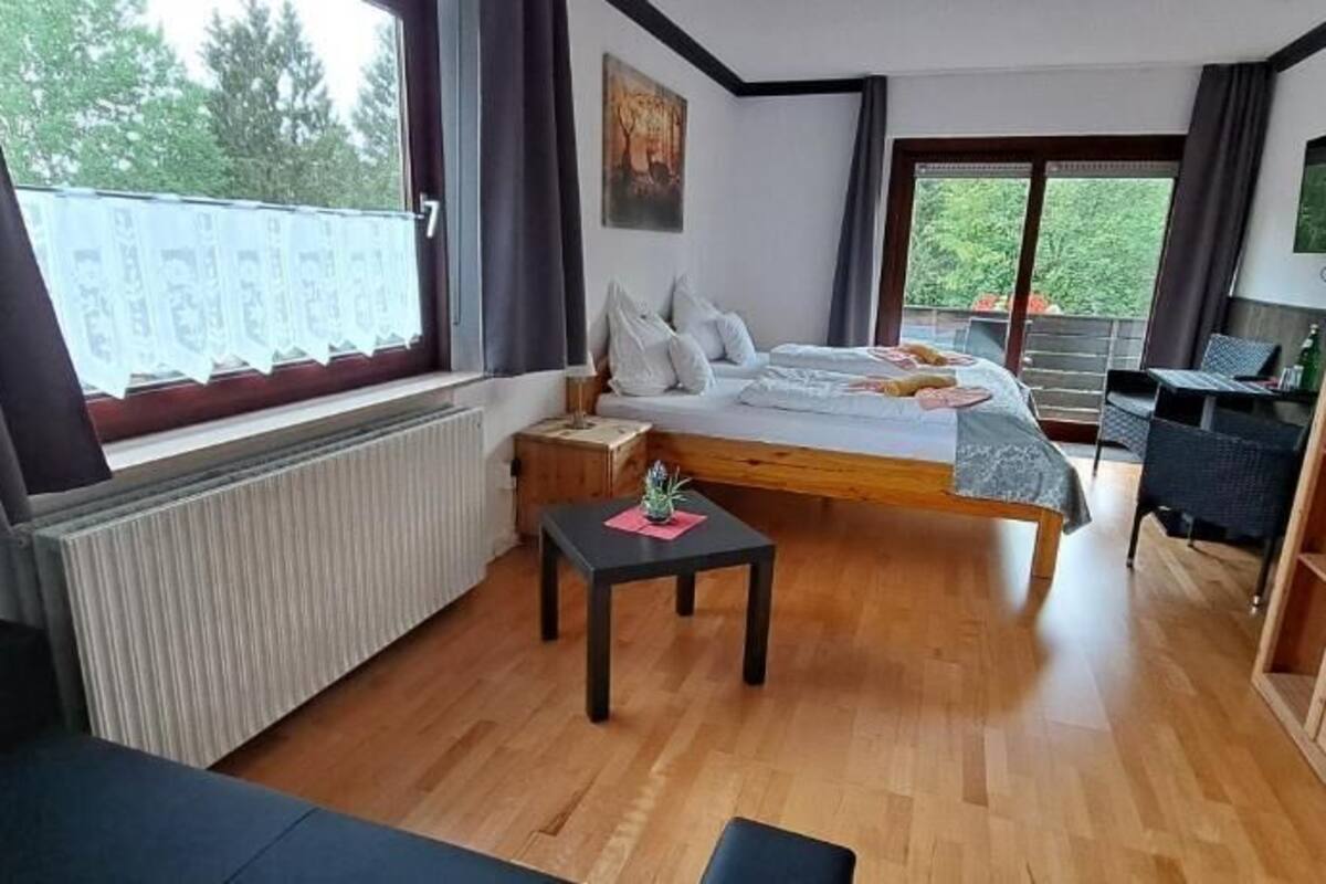 Une chambre avec un lit, une petite table, une armoire et une vue sur l’extérieur.