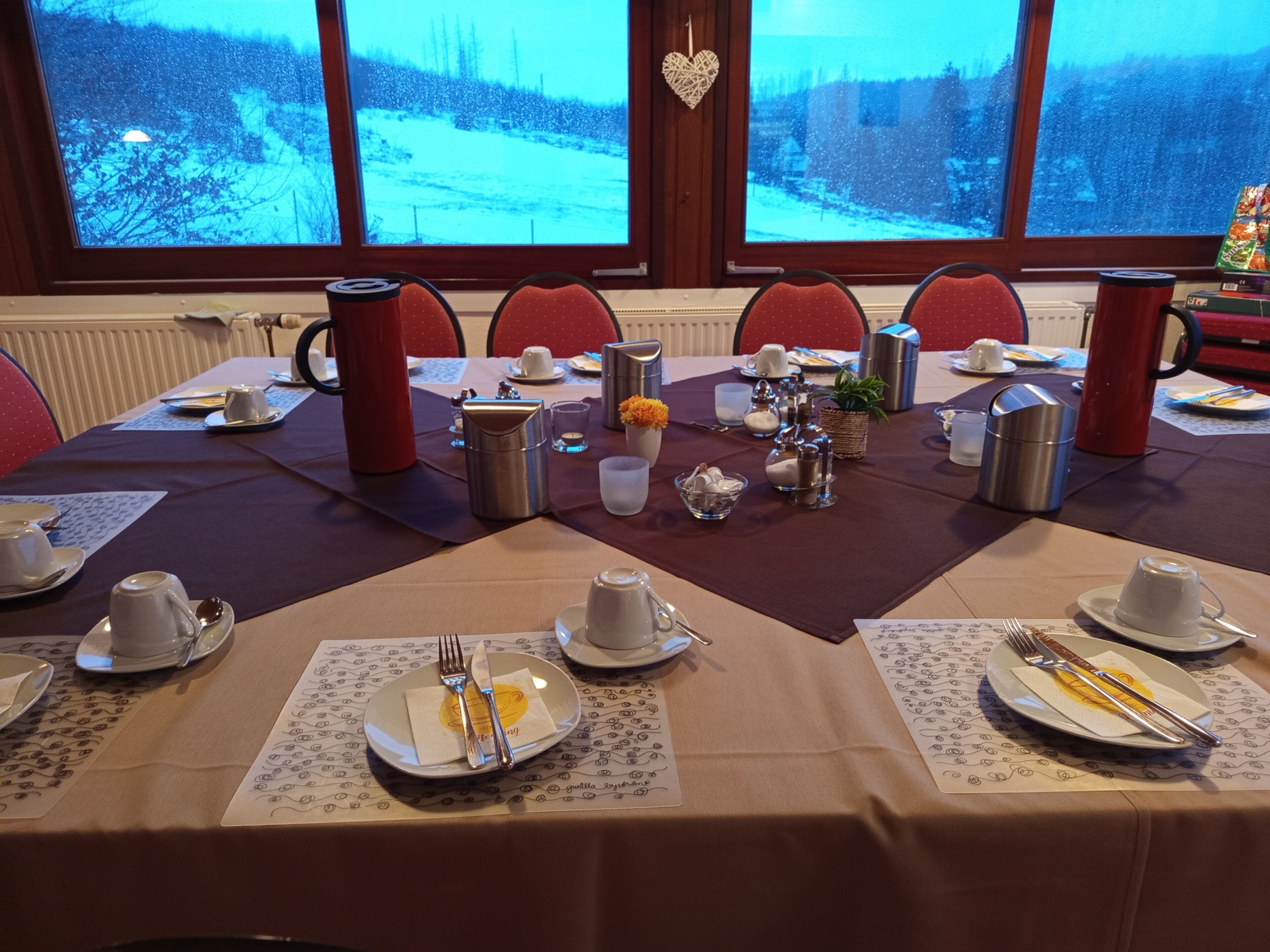 Una mesa de comedor preparada para una comida, con varios platos, cubiertos y cristalería.