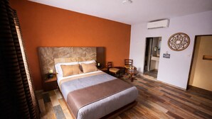 A hotel room with a large bed, wooden flooring, an air conditioning unit, a small table with chairs, and a decorative wall piece. - Auto Hotel Express (Córdoba)
