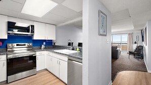 Eine moderne Küche mit Edelstahlgeräten, einem großen Fenster und Blick auf den Strand.