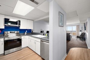Eine moderne Küche mit Edelstahlgeräten, einem großen Fenster und Blick auf den Strand.
