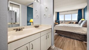 Ein Hotelzimmer mit einem großen Spiegel, zwei Waschbecken, einem Bett mit Blick und einem Balkon.