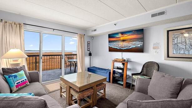 Ein Wohnzimmer mit Glastür zum Balkon, einem Tisch und zwei Sofas.