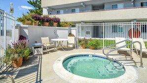 Ein Poolbereich mit Whirlpool, Liegestühlen und Topfpflanzen.