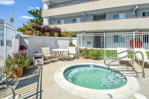 Ein Poolbereich mit Whirlpool, Liegestühlen und Topfpflanzen.
