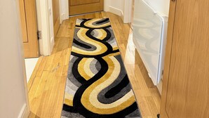 A hallway with wooden flooring, a patterned rug, and wooden doors. - Modern 1-Bed Flat | Cardiff City Centre | Free Parking (Cardiff)