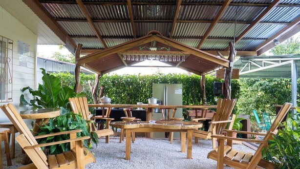 Eine Terrasse im Freien mit Holzmöbeln, einem Grill und einem Kühlschrank.