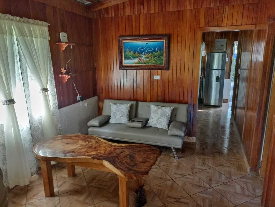 Une pièce aux murs lambrés, avec un canapé, une table basse et un tableau accroché au mur.