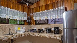Eine Küche mit Holzwänden, einem Spülbecken, einem Herd, einer Kaffeemaschine und einem Kühlschrank.