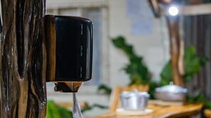 Ein Holztisch mit einem schwarzen Spender, der eine Flüssigkeit, vermutlich Kaffee oder Tee, ausgibt, in einem Restaurantambiente.