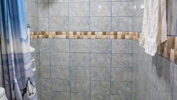 A bathroom with a shower, toilet, and blue rug.
