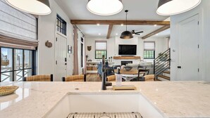 Una cocina amplia con una isla grande, iluminación colgante y vistas al comedor.