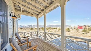 Un porche techado con sillas de madera y vistas a un paisaje desértico con montañas.