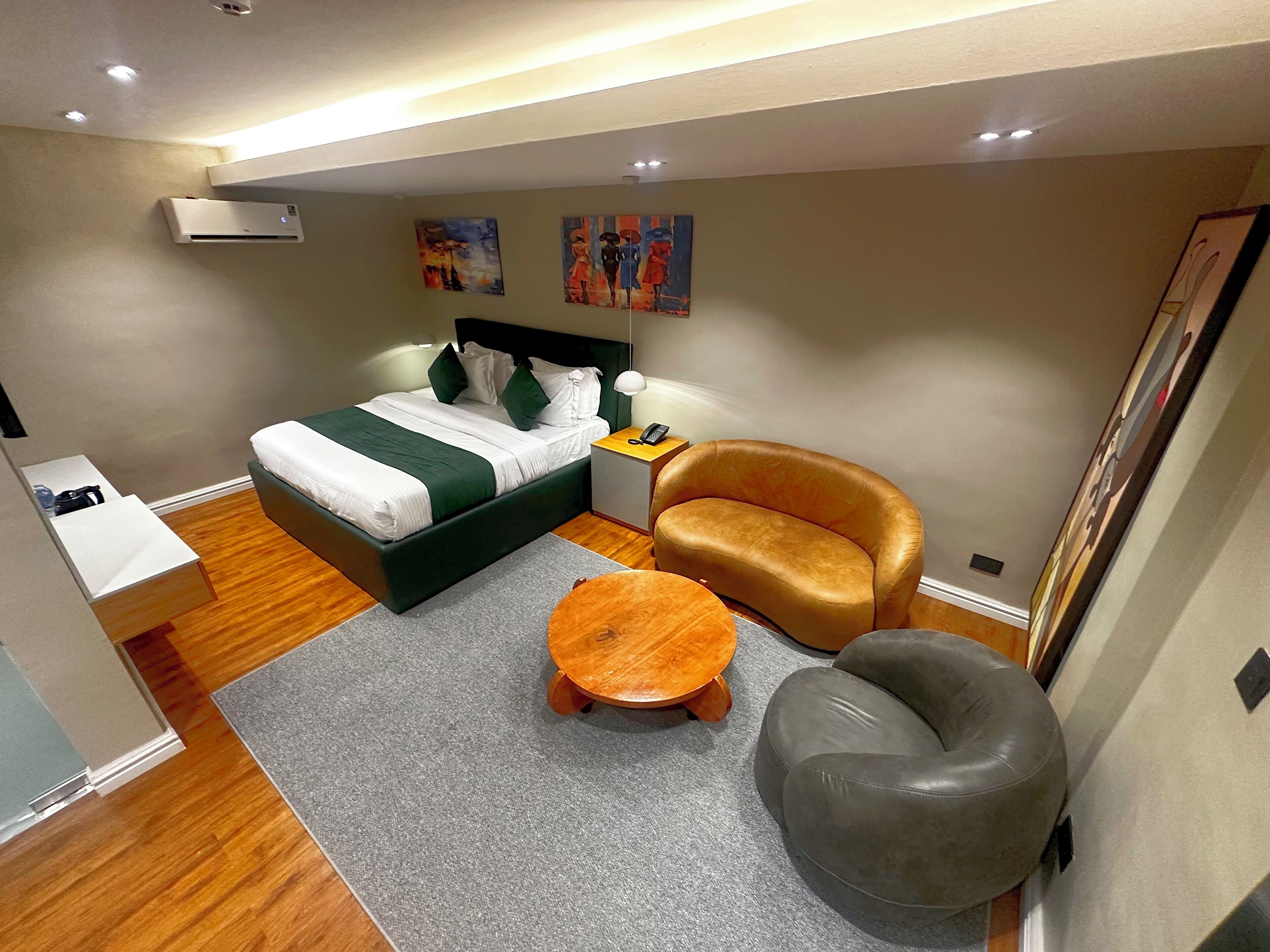 A compact hotel room with a bed, a sofa, a small round table, and a chair.
