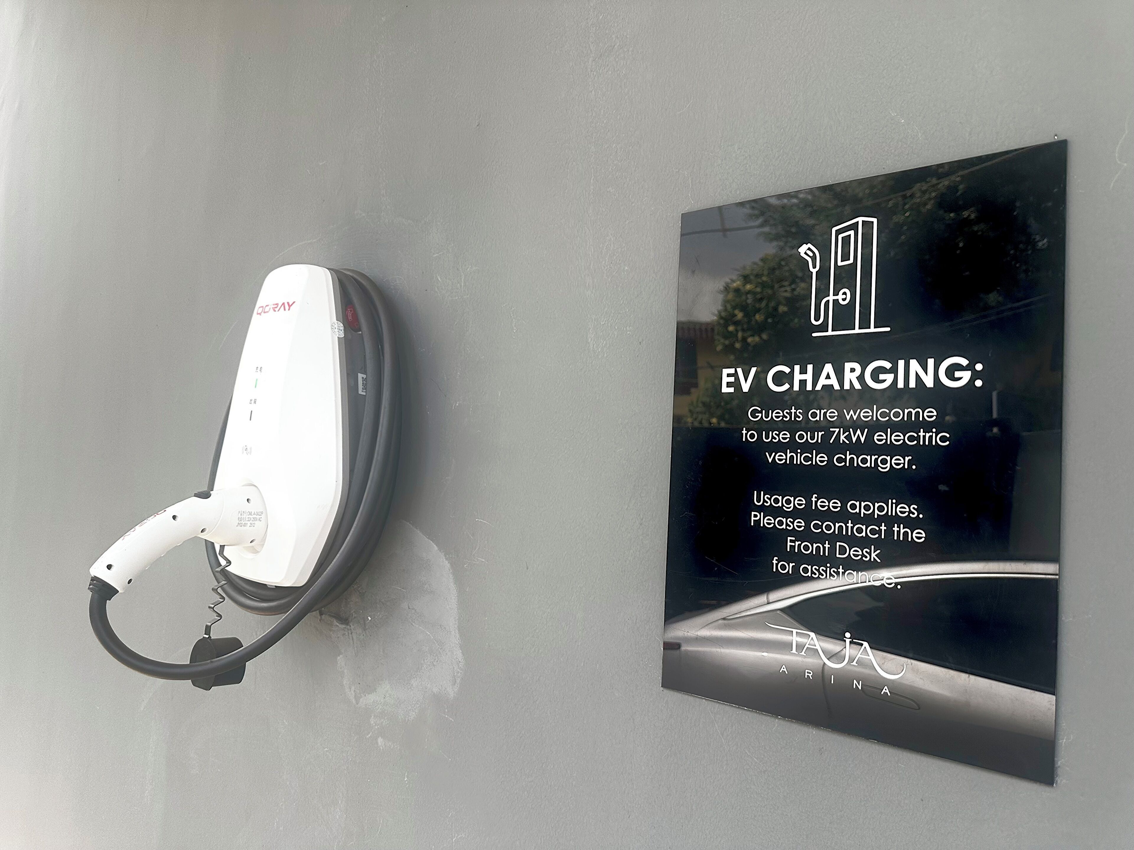 Une borne de recharge pour véhicules électriques et un panneau indiquant les heures de disponibilité de la recharge et les tarifs applicables.
