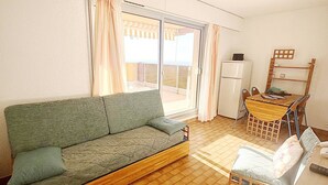 Espai habitable compacte amb sofà, taula de dinar i nevera.