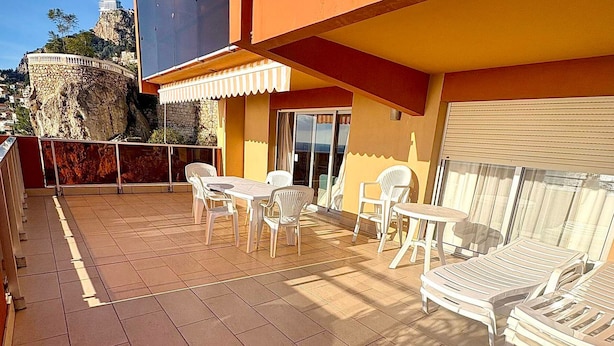 Una terrassa amb taula i cadires, una taula petita i una cadira relax.