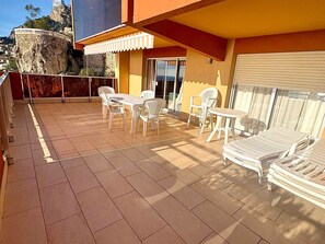 Eine Terrasse mit Tisch und Stühlen, einem kleinen Tisch und einem Liegestuhl.