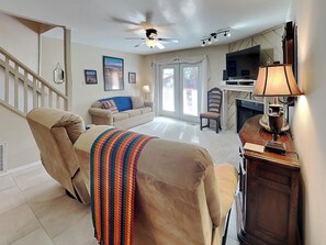 A spacious living room with a large recliner, a sofa, a fireplace, and a television. - Whispering Bluff #402 (Ruidoso)