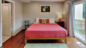 A bedroom with a bed, a ceiling fan, a window with curtains, and a door. - Yellow Belle on Avenue L (Galveston)