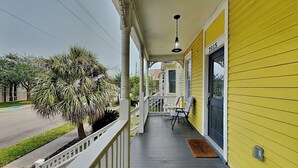 A porch with a railing, a bench, and a door marked '2015'. - Yellow Belle on Avenue L (Galveston)