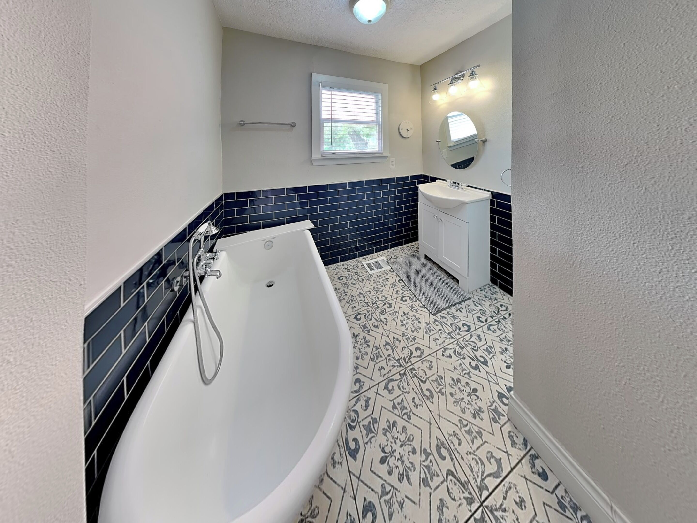 Un baño con una bañera independiente, un lavabo, un espejo y una ventana.
