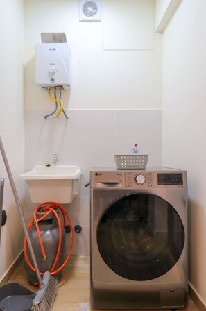Ein Waschbereich mit Waschmaschine, Spüle und Heizung.