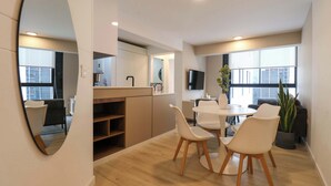 A modern kitchen with built-in appliances, a dining area with a round table and chairs, and a large mirror. - w* | Amazing 1BR Apartment in Heart of San Isidro (San Isidro)