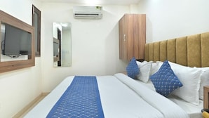 Habitación de hotel con cama, cabecero de madera, espejo y unidad de aire acondicionado.