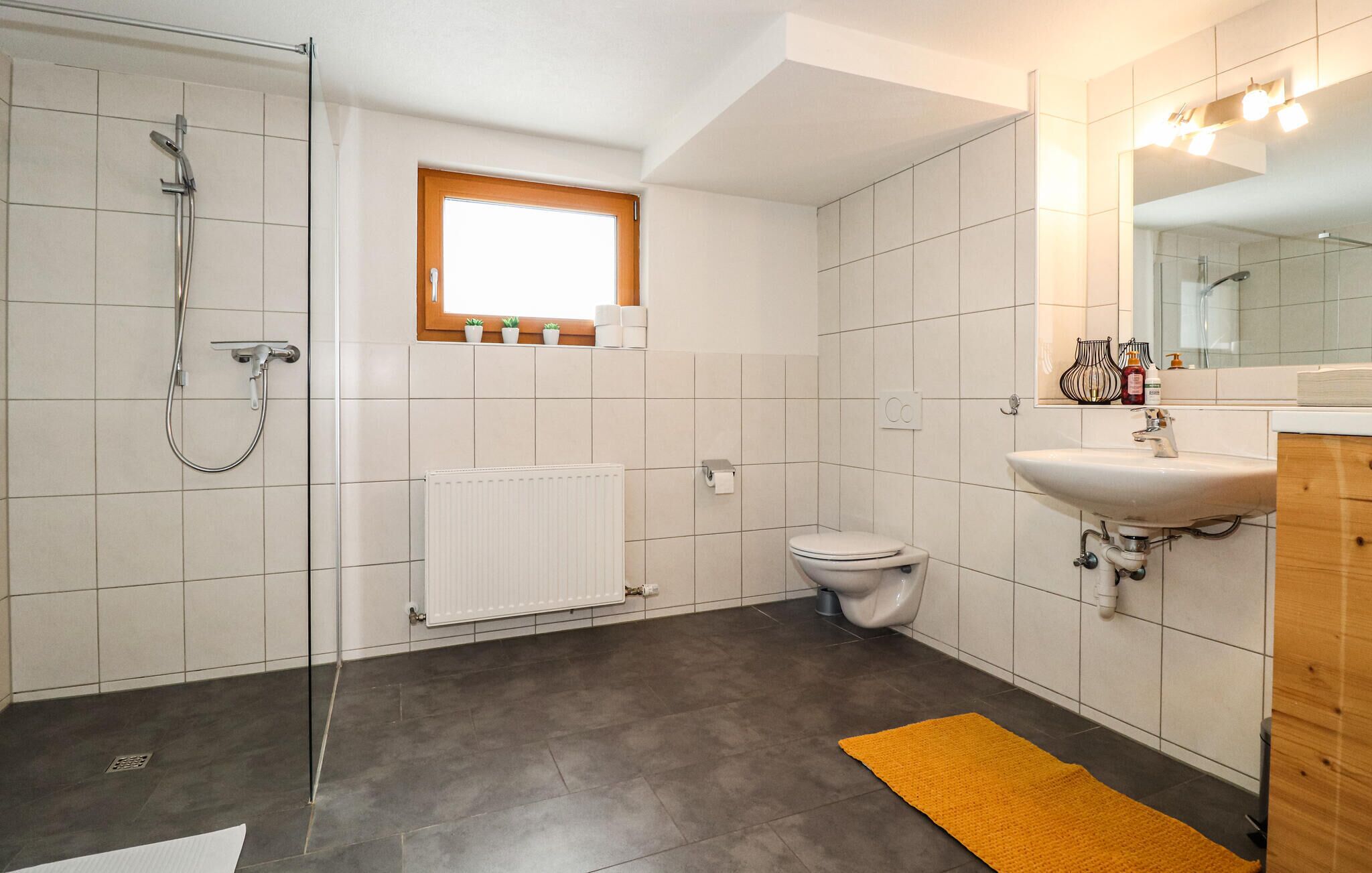 A modern bathroom with a shower, toilet, and sink.