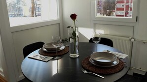 Une table à manger dressée avec des assiettes, des couverts et un vase contenant une seule rose.