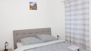 Une chambre à coucher avec un lit, une table de chevet, un tableau au mur et un rideau à rayures.
