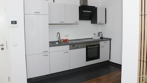 Une cuisine moderne avec des meubles blancs, un four noir et un évier en acier inoxydable.