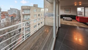 Eine moderne Wohnung mit Balkon, großen Fenstern und einem roten Sofa.