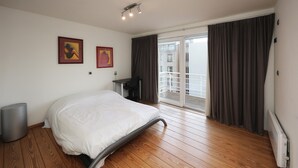 Ein Hotelzimmer mit Bett, Schreibtisch und Blick auf einen Balkon.