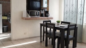 Ett kompakt bostadsutrymme med ett litet kök, en matplats med bord och stolar samt en soffa.