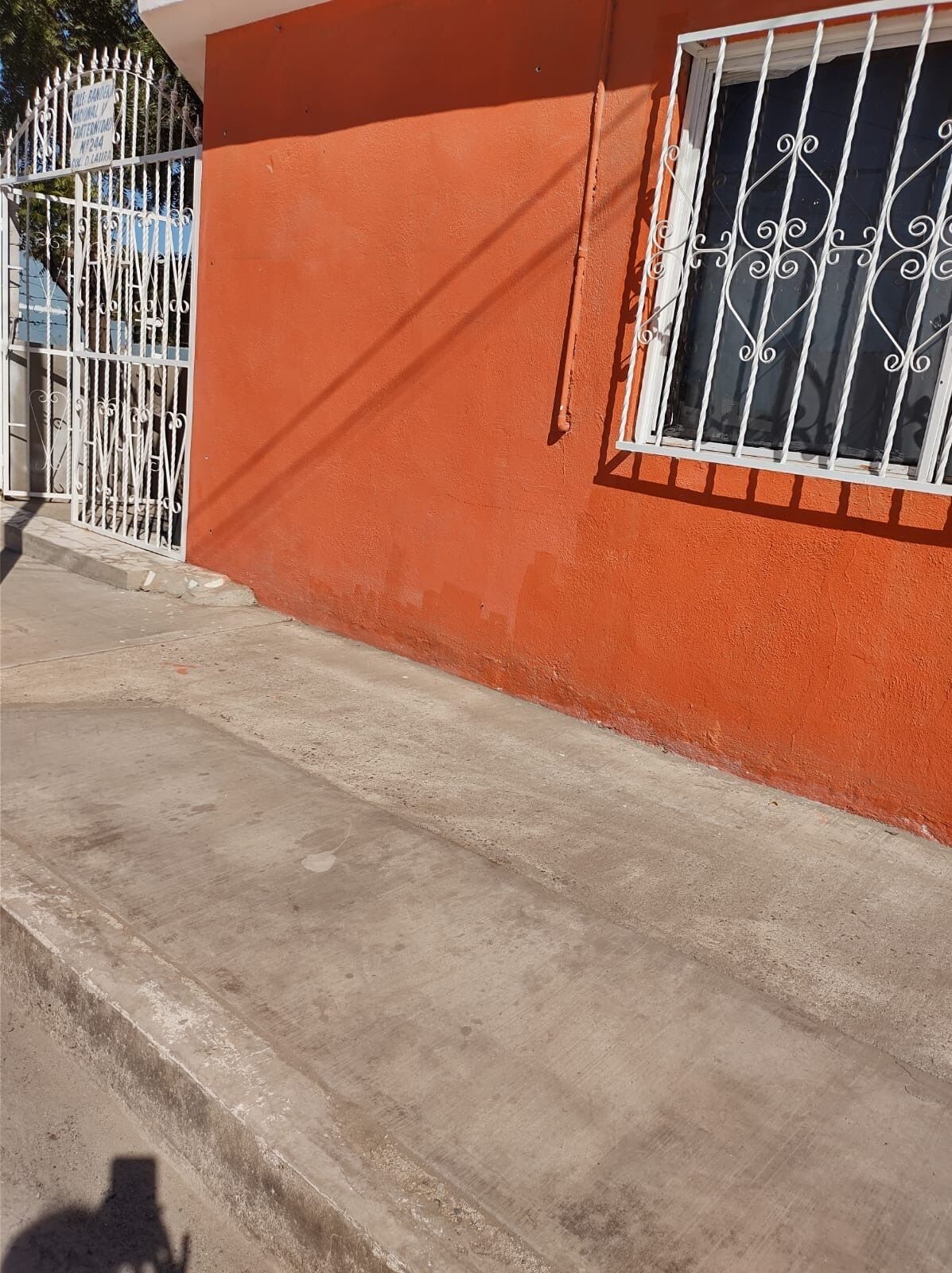 A building with a concrete staircase leading to a door with a metal gate.