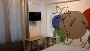 Une chambre d’hôtel avec deux lits, un bureau, une chaise et un téléviseur fixé au mur.