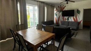 Un coin repas avec une table et des chaises en bois, un canapé et un téléviseur fixé au mur.