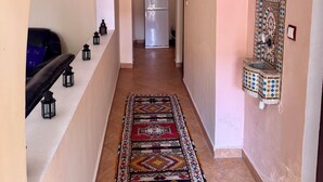 A hallway with a patterned rug, a refrigerator, and a wall-mounted sink. - Villa Riad Style (with garden access) - Wifi and Parking (Agadir)