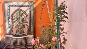 A tiled courtyard with a decorative tile wall, potted plants, and a small fountain. - Villa Riad Style (with garden access) - Wifi and Parking (Agadir)