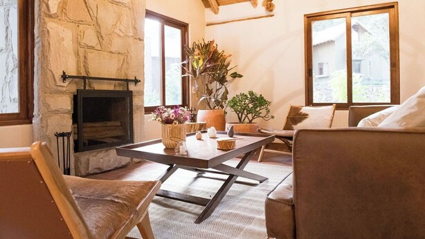 A cozy living room with a stone fireplace, comfortable seating, and large windows offering a view of the outdoors. - Killay B1 - Gorgeous 3-bedroom villa in Calca perfect for your getaway (Calca)