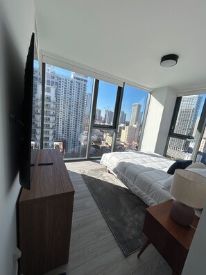 A modern bedroom with a large bed, a flat-screen TV, and a view of a cityscape through floor-to-ceiling windows. - Miami-Brickell Skyline Lux High Rise 2BR-2B -walking distance to KASEYA-BAYSIDE (Miami)
